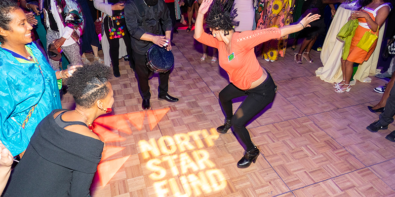 Someone dancing at the Community Gala to celebrate grassroots organizing. The North Star Fund logo is projected on the dance floor.