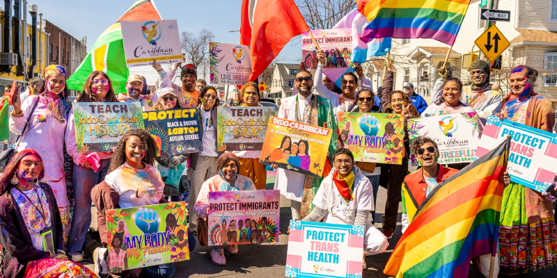 Caribbean Equality Project members holding pride signs outside.